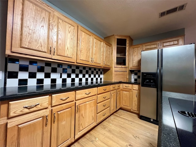 kitchen featuring backsplash, stainless steel fridge with ice dispenser, light hardwood / wood-style floors, and dark stone countertops