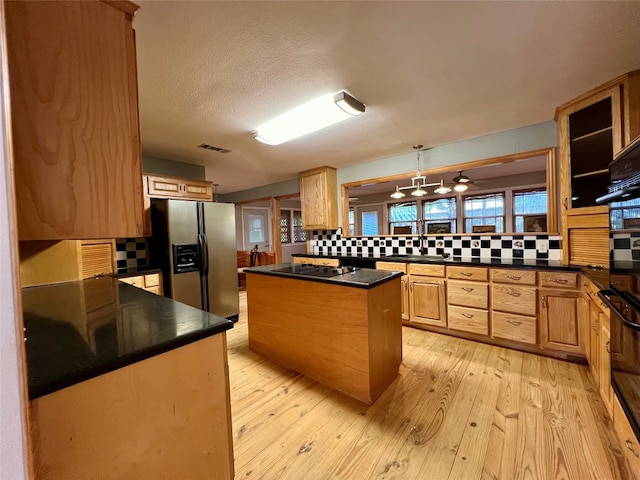 kitchen with light hardwood / wood-style flooring, pendant lighting, tasteful backsplash, and stainless steel fridge