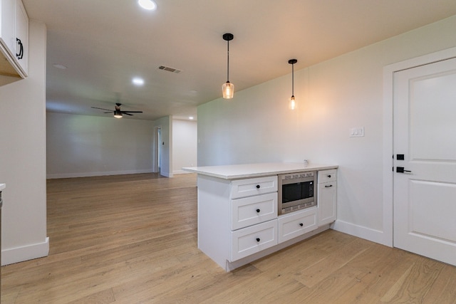 kitchen with white cabinets, ceiling fan, light wood-type flooring, and pendant lighting