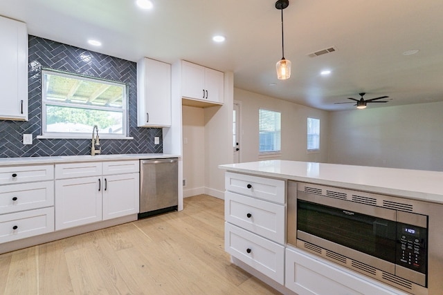 kitchen featuring hanging light fixtures, ceiling fan, light hardwood / wood-style flooring, stainless steel appliances, and tasteful backsplash