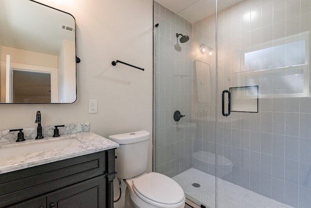 bathroom with toilet, vanity, and a shower with shower door