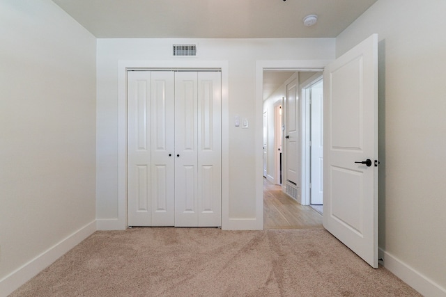 unfurnished bedroom featuring a closet and light carpet