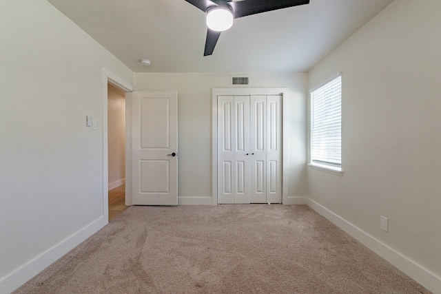 unfurnished bedroom with light colored carpet, a closet, and ceiling fan