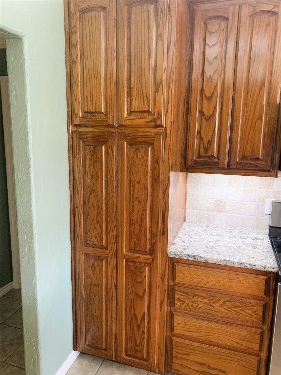 kitchen with tasteful backsplash, light stone counters, and light tile patterned floors