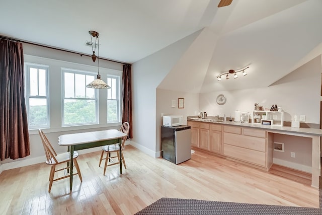 kitchen with decorative light fixtures, light brown cabinets, light hardwood / wood-style floors, ceiling fan, and lofted ceiling