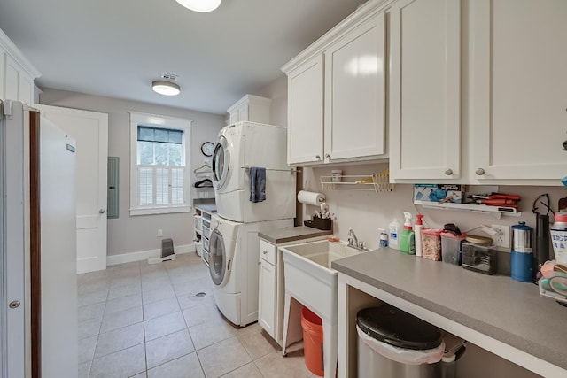 laundry room featuring stacked washer / drying machine, light tile flooring, and cabinets