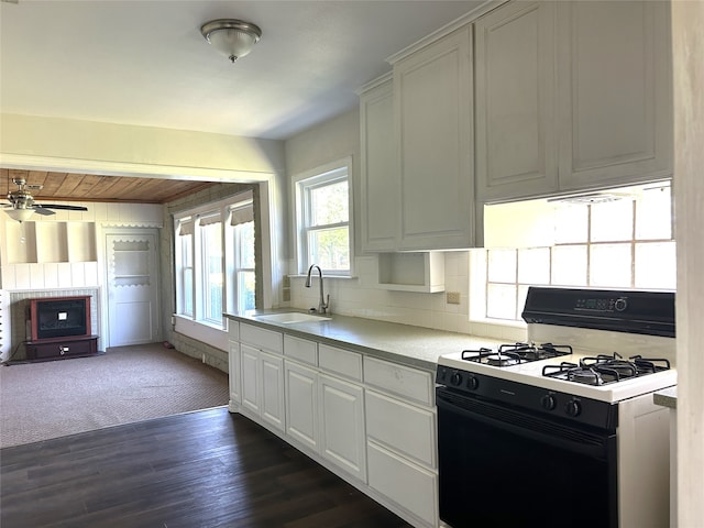 kitchen featuring white cabinetry, white gas range, dark colored carpet, ceiling fan, and sink