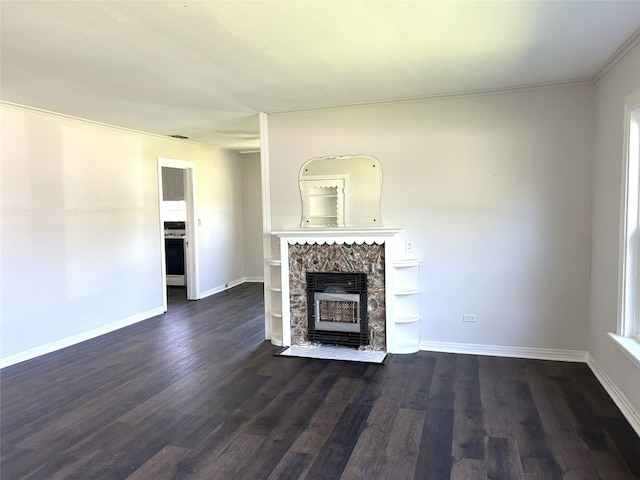 unfurnished living room featuring ornamental molding, dark hardwood / wood-style flooring, and a stone fireplace