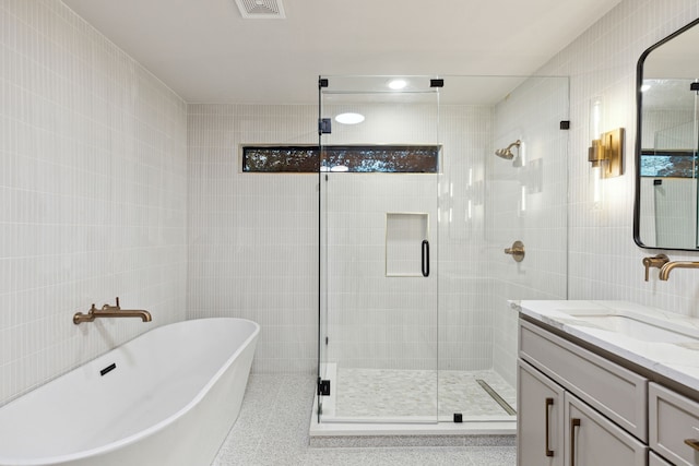 bathroom featuring vanity, tile walls, and shower with separate bathtub