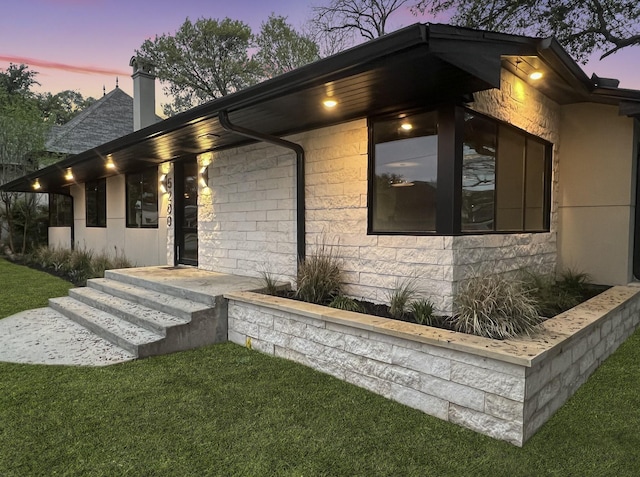 property exterior at dusk featuring a lawn