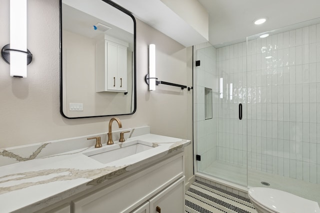 bathroom featuring tile patterned floors, vanity, toilet, and a shower with shower door