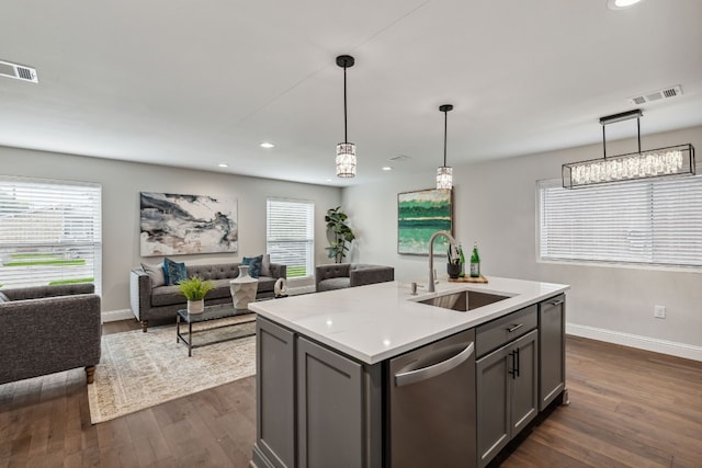 kitchen featuring sink, gray cabinets, stainless steel dishwasher, a kitchen island with sink, and dark hardwood / wood-style flooring