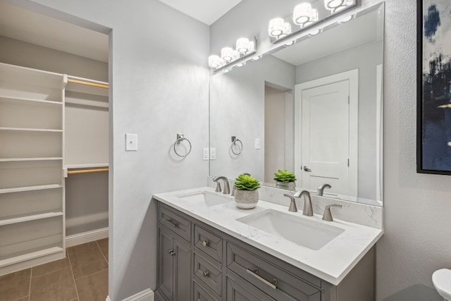 bathroom featuring double vanity, a spacious closet, a sink, and tile patterned floors