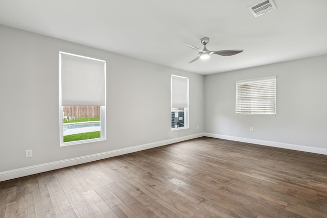 empty room featuring baseboards, visible vents, dark wood finished floors, and a ceiling fan