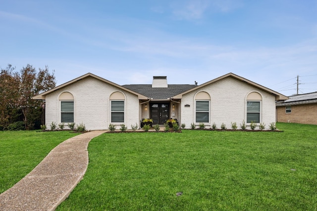 view of front of house with a front yard, a chimney, and brick siding