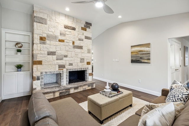 living area featuring lofted ceiling, a stone fireplace, wood finished floors, a ceiling fan, and baseboards