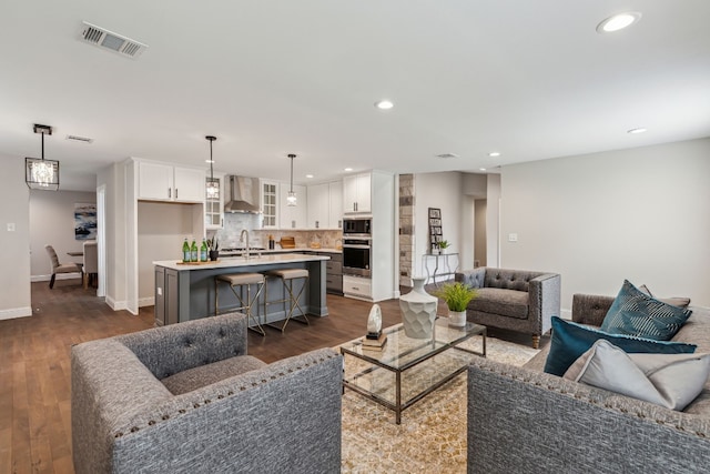 living area with baseboards, visible vents, dark wood finished floors, and recessed lighting