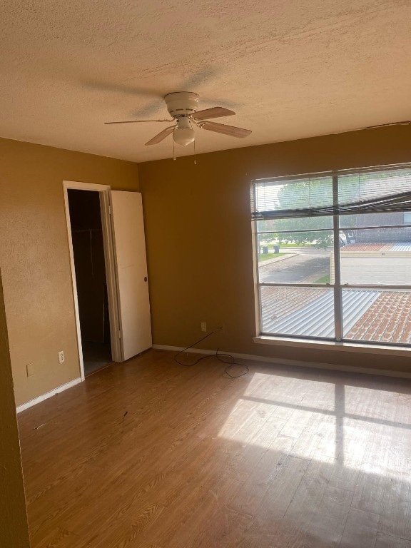 unfurnished room featuring wood-type flooring, ceiling fan, and a textured ceiling