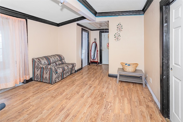 sitting room featuring light hardwood / wood-style flooring, crown molding, and beam ceiling