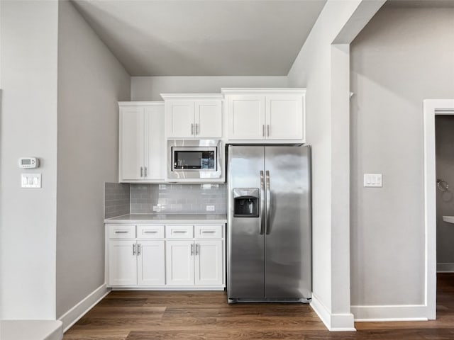 kitchen featuring dark hardwood / wood-style flooring, backsplash, white cabinetry, and stainless steel appliances