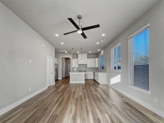 unfurnished living room with ceiling fan, hardwood / wood-style flooring, and sink