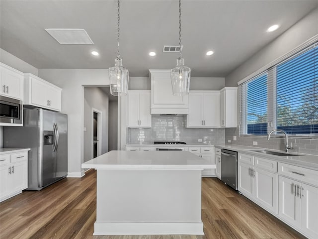 kitchen with dark hardwood / wood-style floors, appliances with stainless steel finishes, a center island, and sink