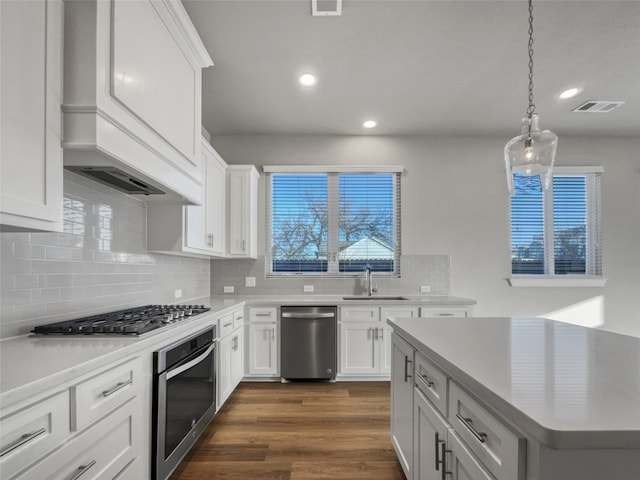 kitchen featuring white cabinets, appliances with stainless steel finishes, backsplash, and dark hardwood / wood-style flooring