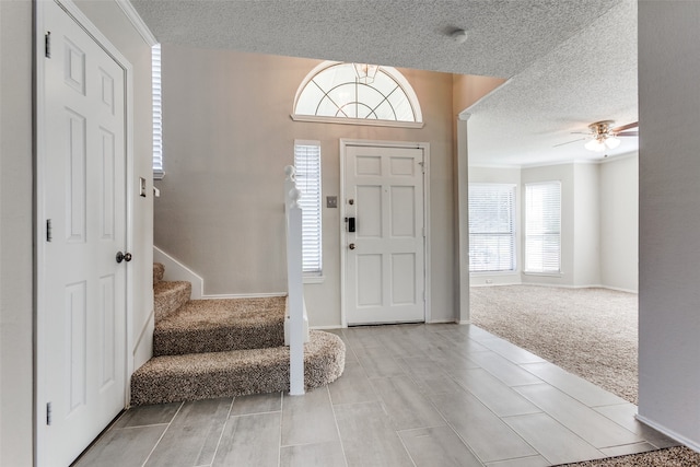 foyer featuring a textured ceiling, ceiling fan, light carpet, and a wealth of natural light