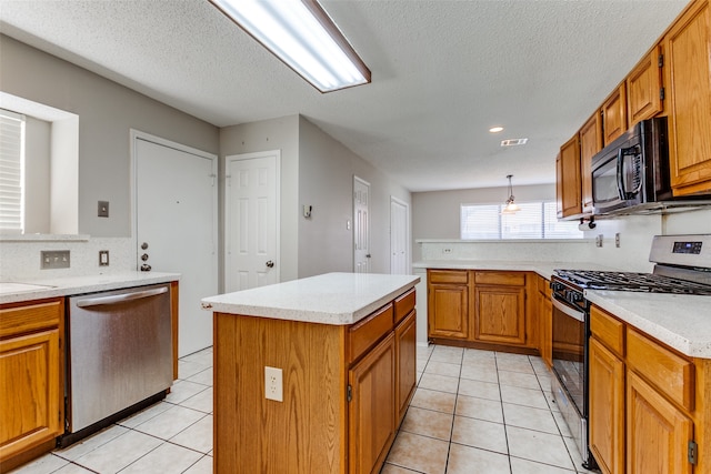 kitchen with a textured ceiling, a center island, hanging light fixtures, stainless steel appliances, and light tile patterned floors