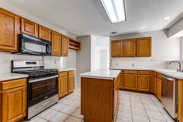 kitchen featuring a textured ceiling, a center island, light tile patterned flooring, sink, and appliances with stainless steel finishes