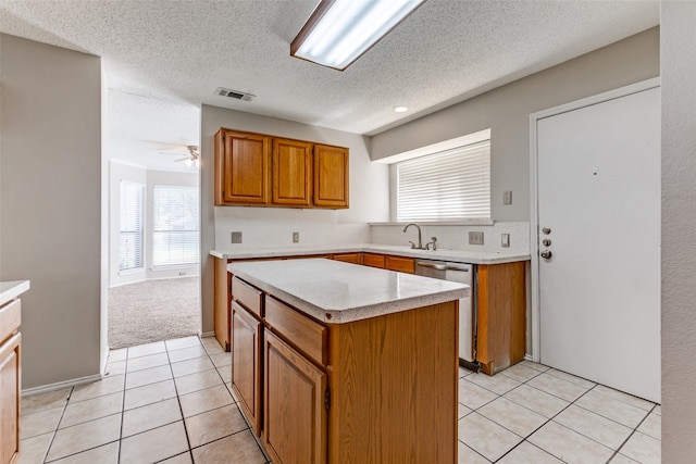 kitchen with ceiling fan, light tile patterned flooring, a kitchen island, a textured ceiling, and dishwasher