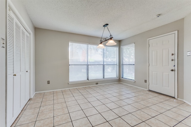 interior space with a textured ceiling and light tile patterned flooring