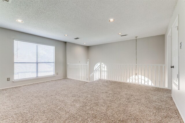 empty room with carpet floors and a textured ceiling