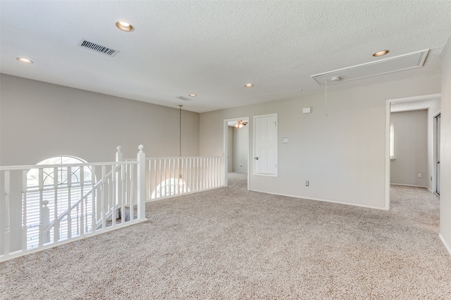 spare room featuring a textured ceiling and light carpet