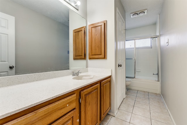 full bathroom with vanity, toilet, a textured ceiling, combined bath / shower with glass door, and tile patterned flooring