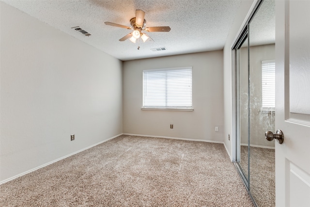 unfurnished bedroom featuring a textured ceiling, carpet, ceiling fan, and a closet