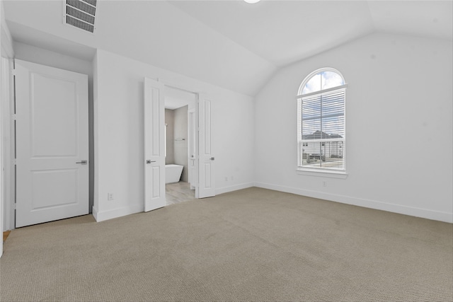 unfurnished bedroom featuring ensuite bathroom, lofted ceiling, and light carpet