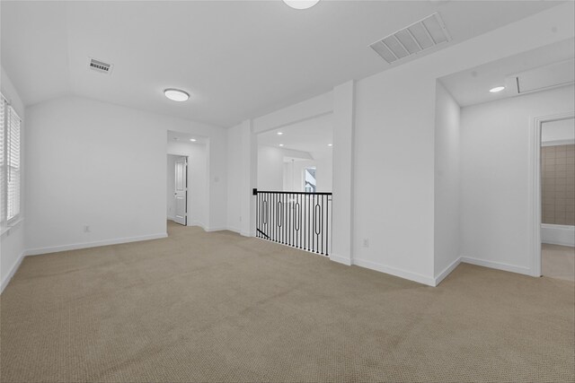 empty room featuring a wealth of natural light, lofted ceiling, and light colored carpet