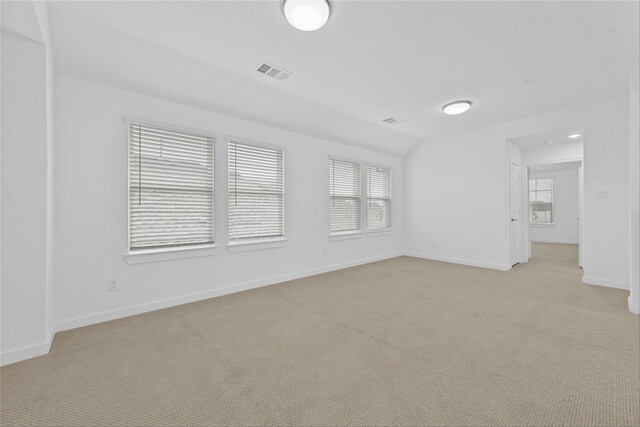 spare room featuring vaulted ceiling and light carpet