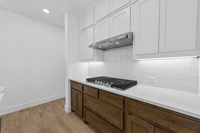 kitchen with white cabinetry, ventilation hood, light hardwood / wood-style floors, stainless steel gas cooktop, and decorative backsplash