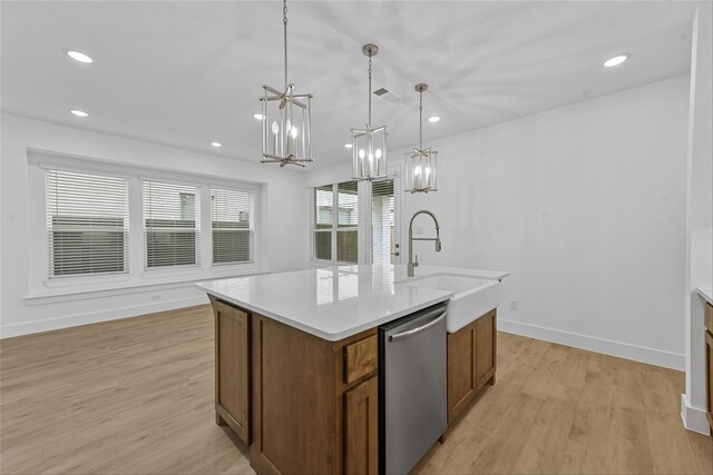 kitchen with pendant lighting, sink, light hardwood / wood-style floors, an island with sink, and stainless steel dishwasher