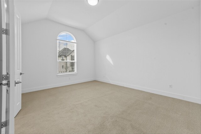 additional living space featuring lofted ceiling and light carpet