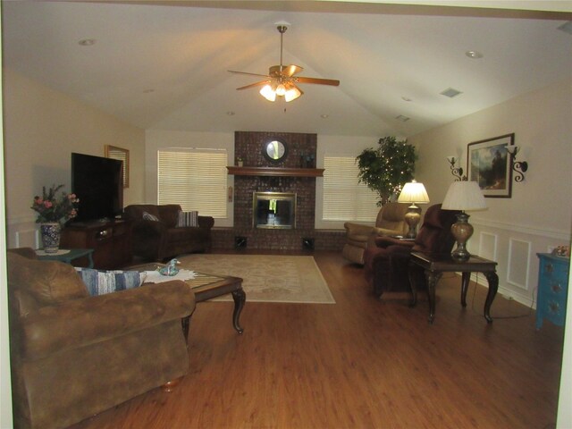 living room featuring ceiling fan, a fireplace, brick wall, vaulted ceiling, and hardwood / wood-style flooring