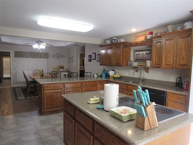 kitchen with dark tile floors, ceiling fan, a kitchen island, and sink