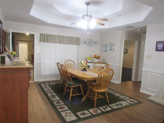 dining area with ceiling fan, a tray ceiling, and dark wood-type flooring