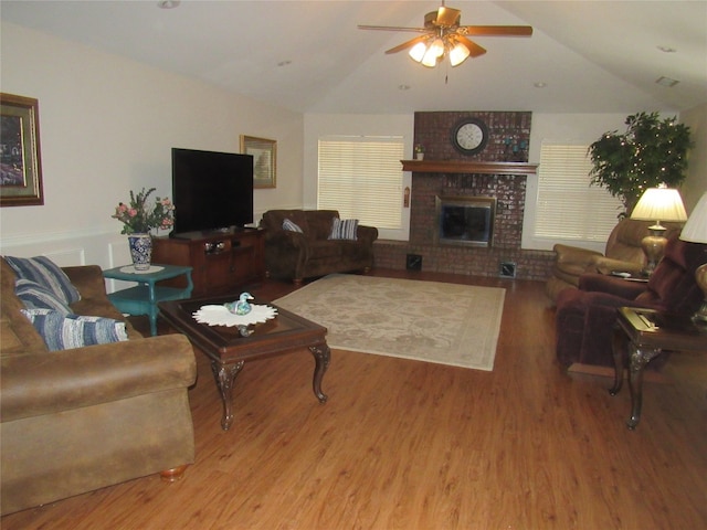 living room with brick wall, vaulted ceiling, a brick fireplace, ceiling fan, and wood-type flooring