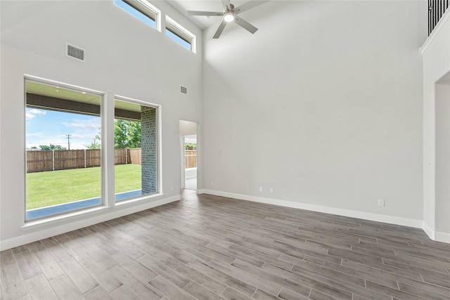 unfurnished room with ceiling fan, hardwood / wood-style floors, and a high ceiling