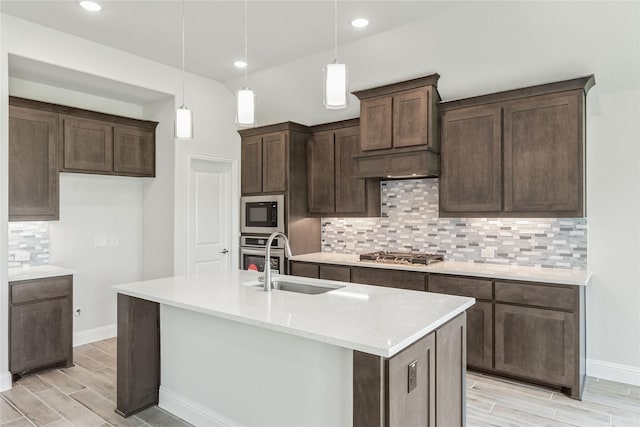 kitchen with stainless steel appliances, sink, an island with sink, and pendant lighting