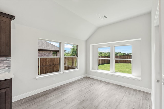 unfurnished dining area featuring a healthy amount of sunlight, light hardwood / wood-style flooring, and vaulted ceiling