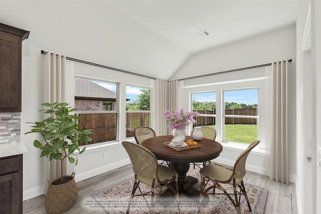 dining room with light hardwood / wood-style floors and vaulted ceiling